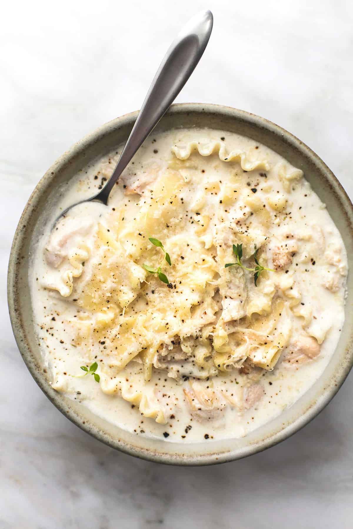 top view of creamy white chicken lasagna soup with a spoon in a bowl.
