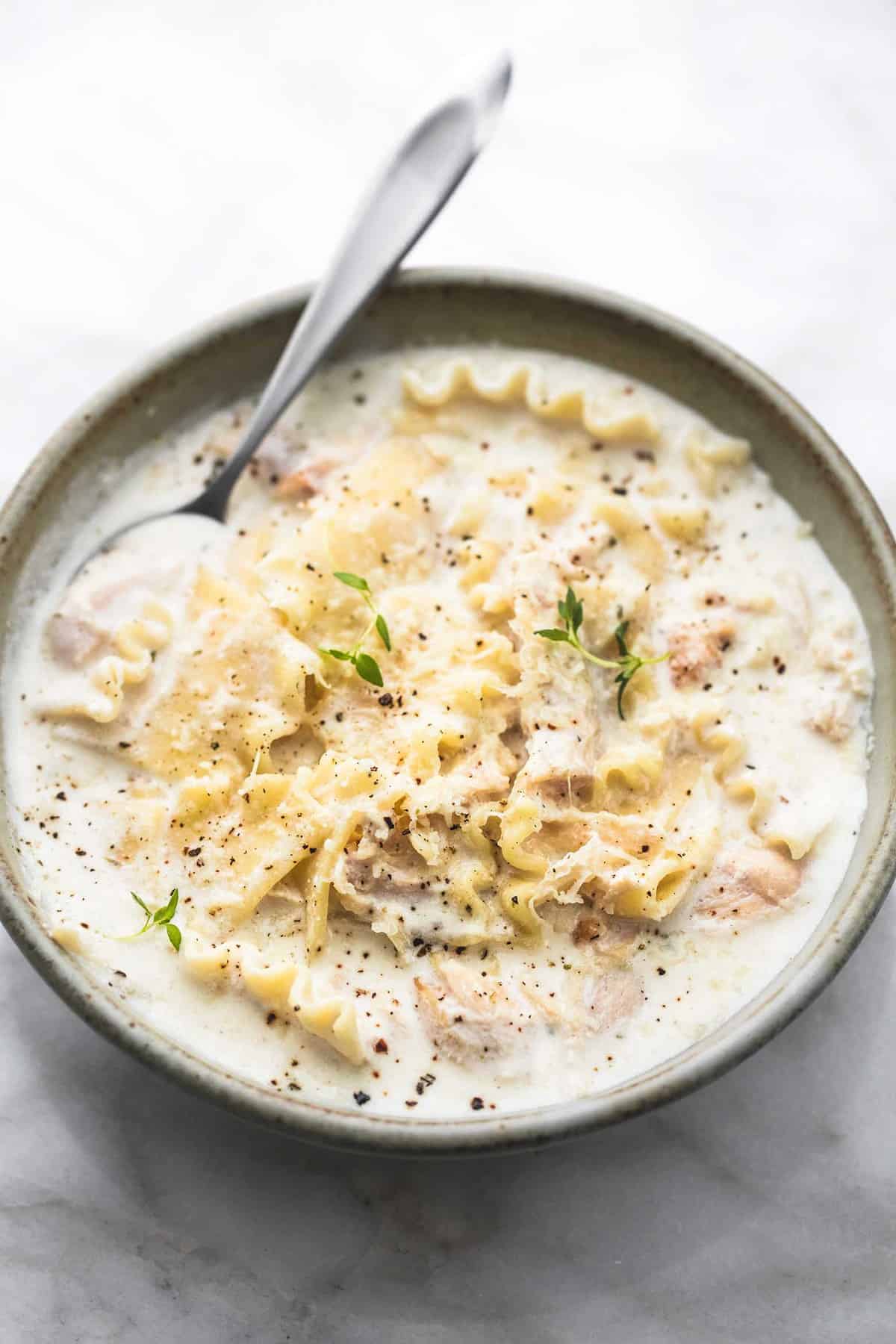 creamy white chicken lasagna soup with a spoon in a bowl.