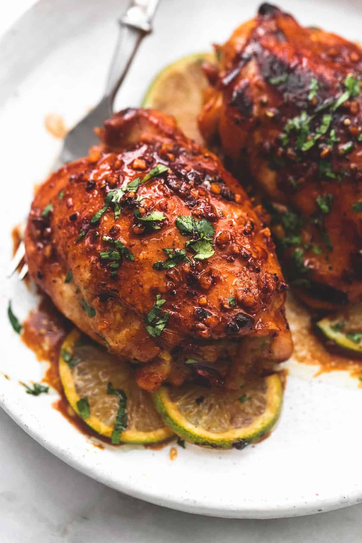 close up of honey lime garlic chicken with a fork on a plate.