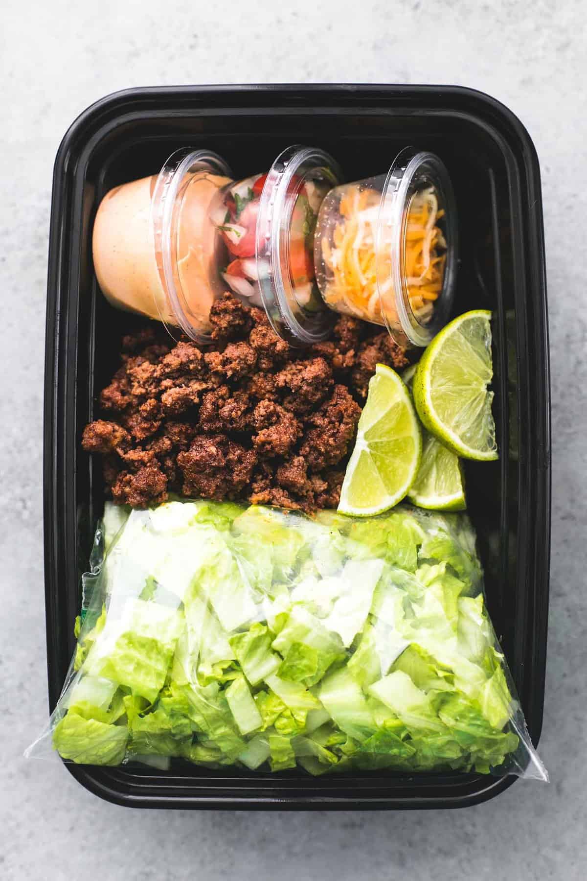 top view of taco salad meal prep in a black tupperware container.