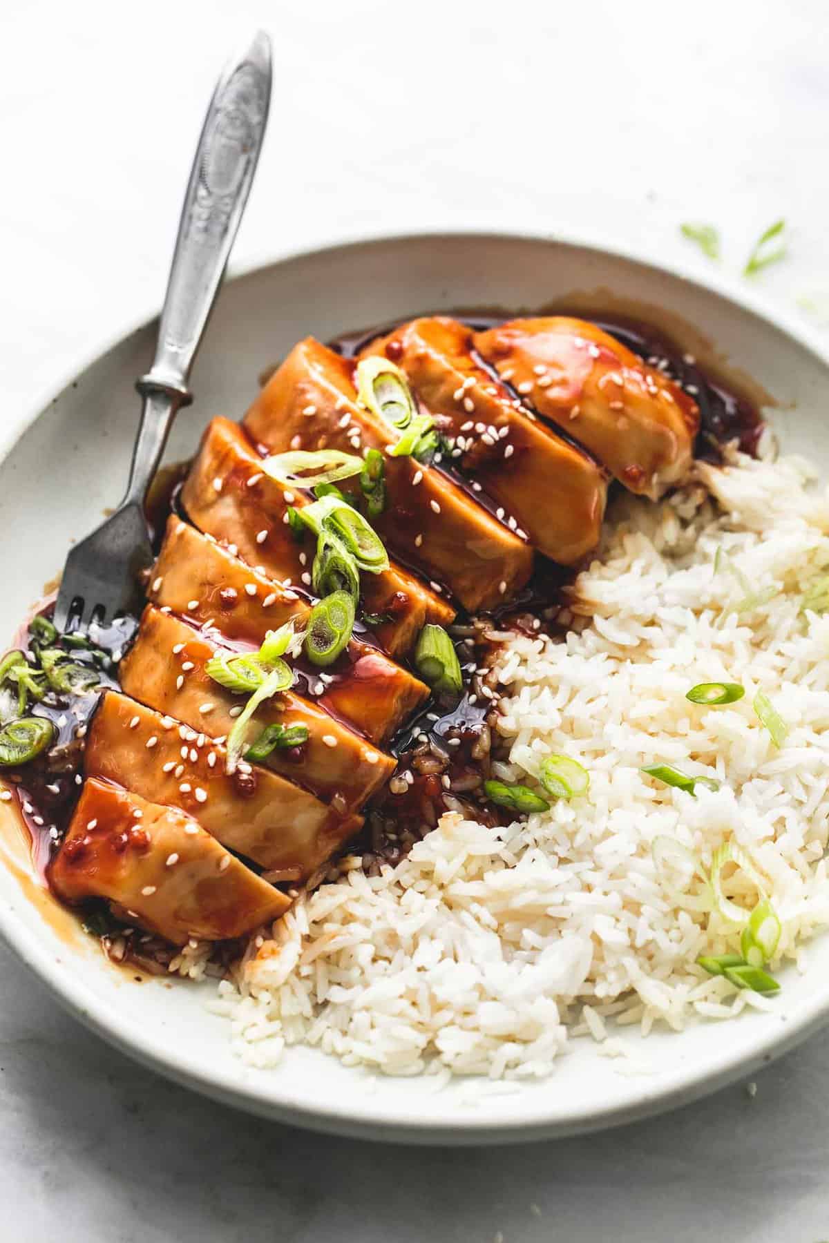 baked teriyaki chicken with rice and a fork on a plate.