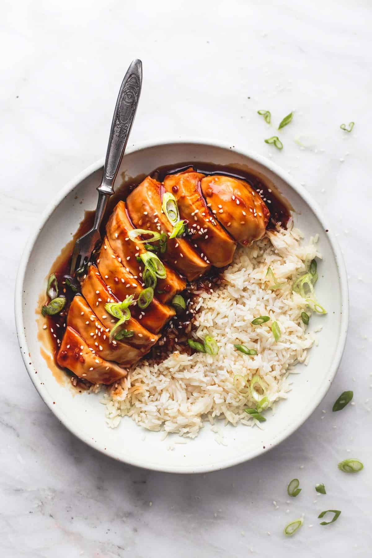 top view of baked teriyaki chicken with rice and a fork on a plate.