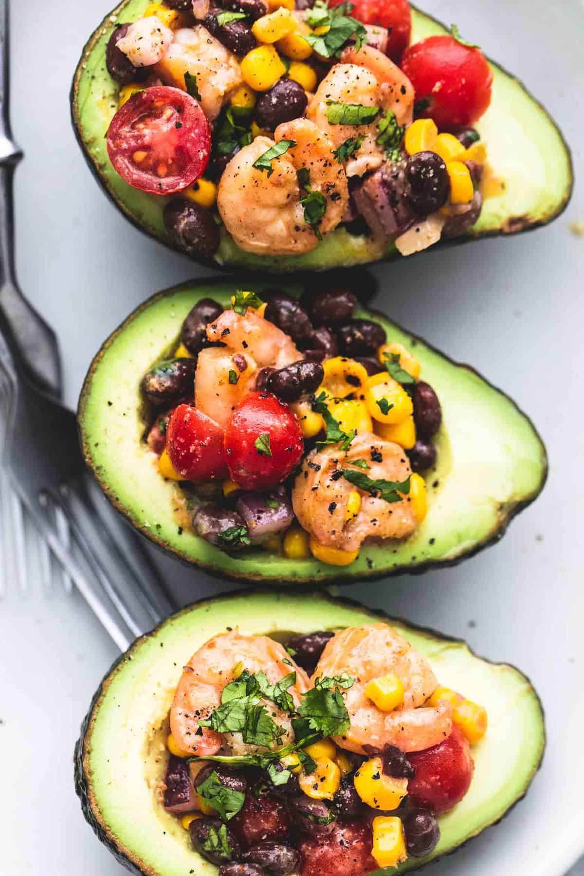 close up top view of Southwest shrimp salad stuffed avocados with forks on the side.