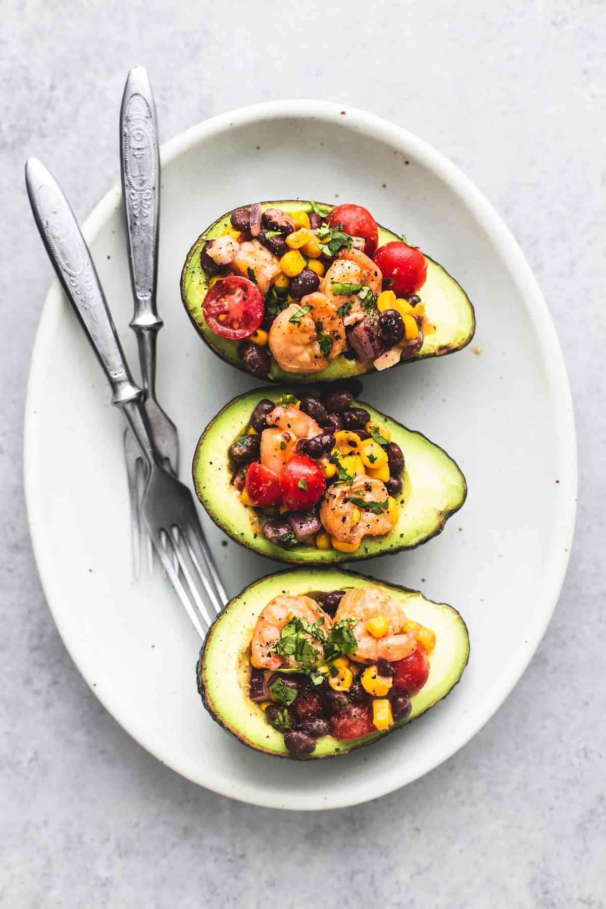 top view of Southwest shrimp salad stuffed avocados with forks on a plate.
