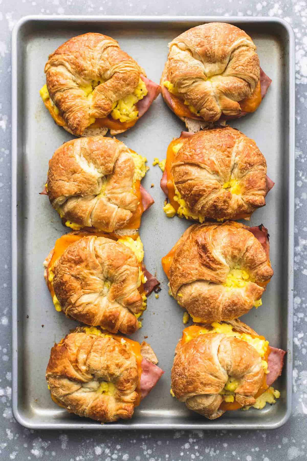 top view of baked croissant breakfast sandwiches on a baking sheet.