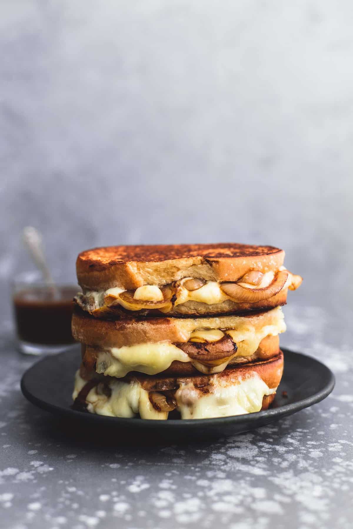stacked French onion grilled cheese sandwiches on a plate.