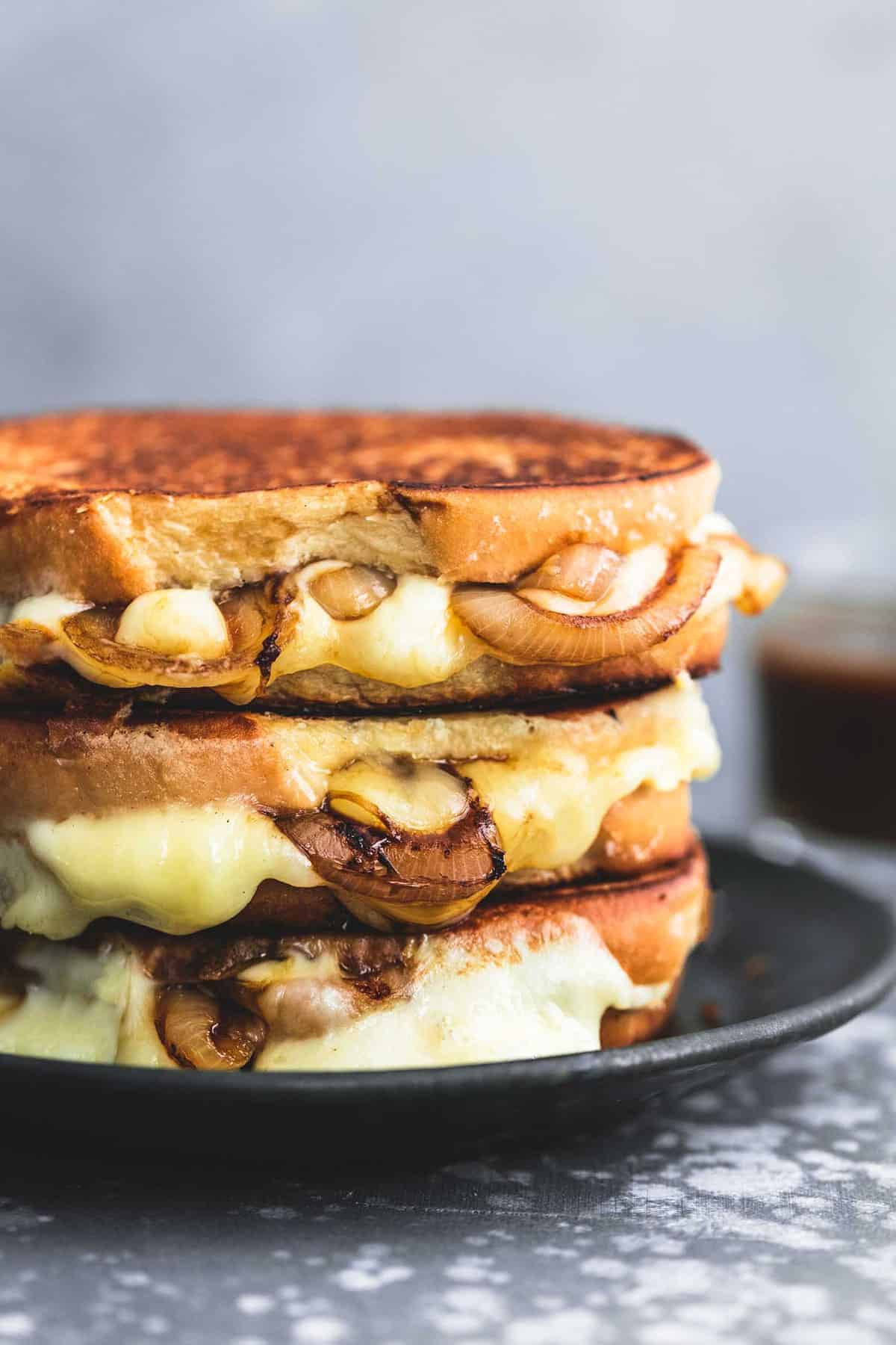 stacked French onion grilled cheese sandwiches on a plate.