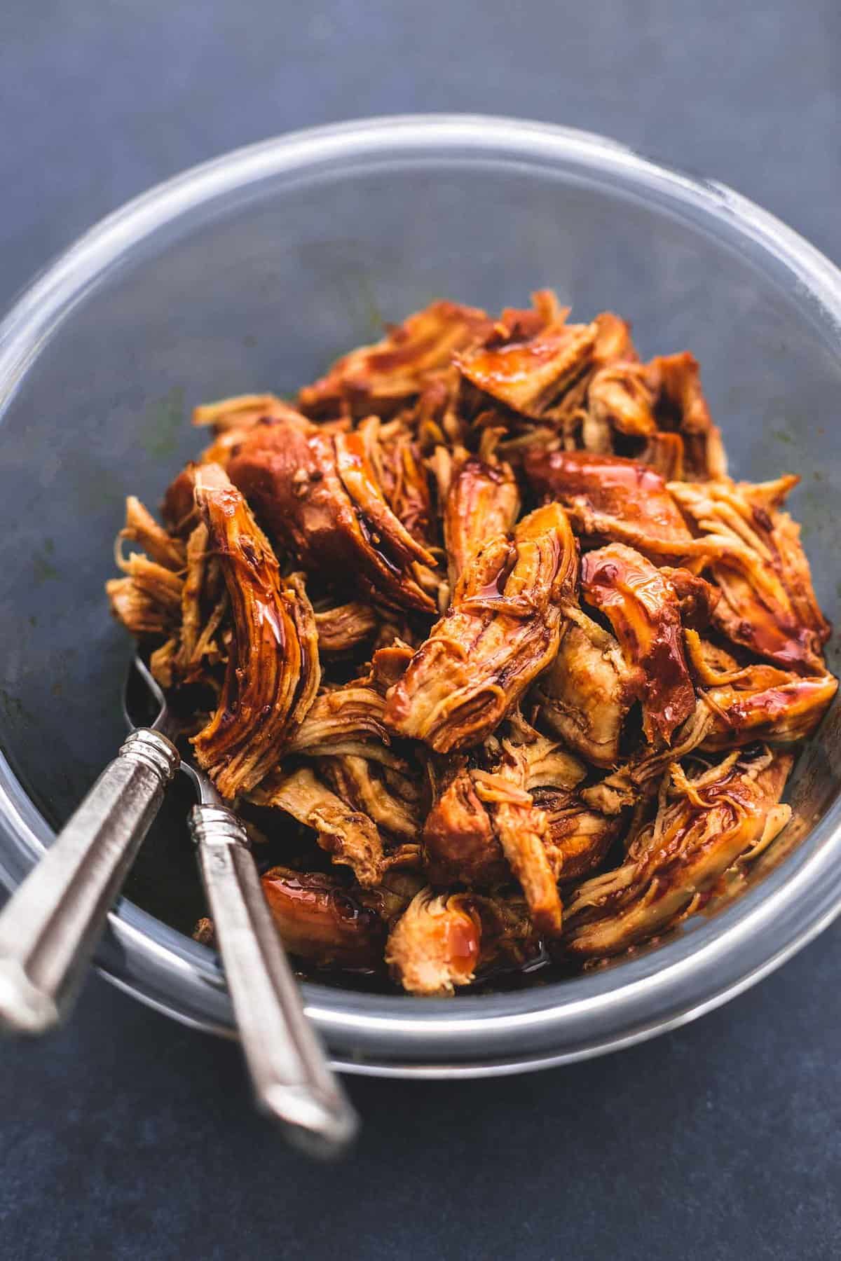 instant pot honey teriyaki chicken with two forks in a glass bowl.