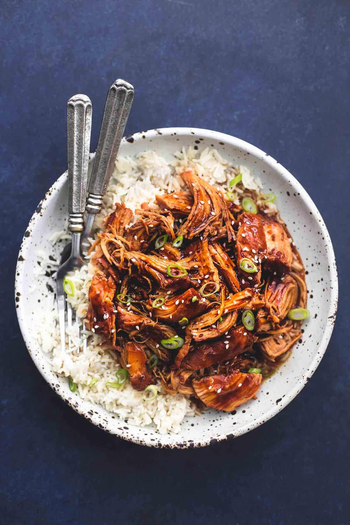 top view of instant pot honey teriyaki chicken with rice and forks on a plate.