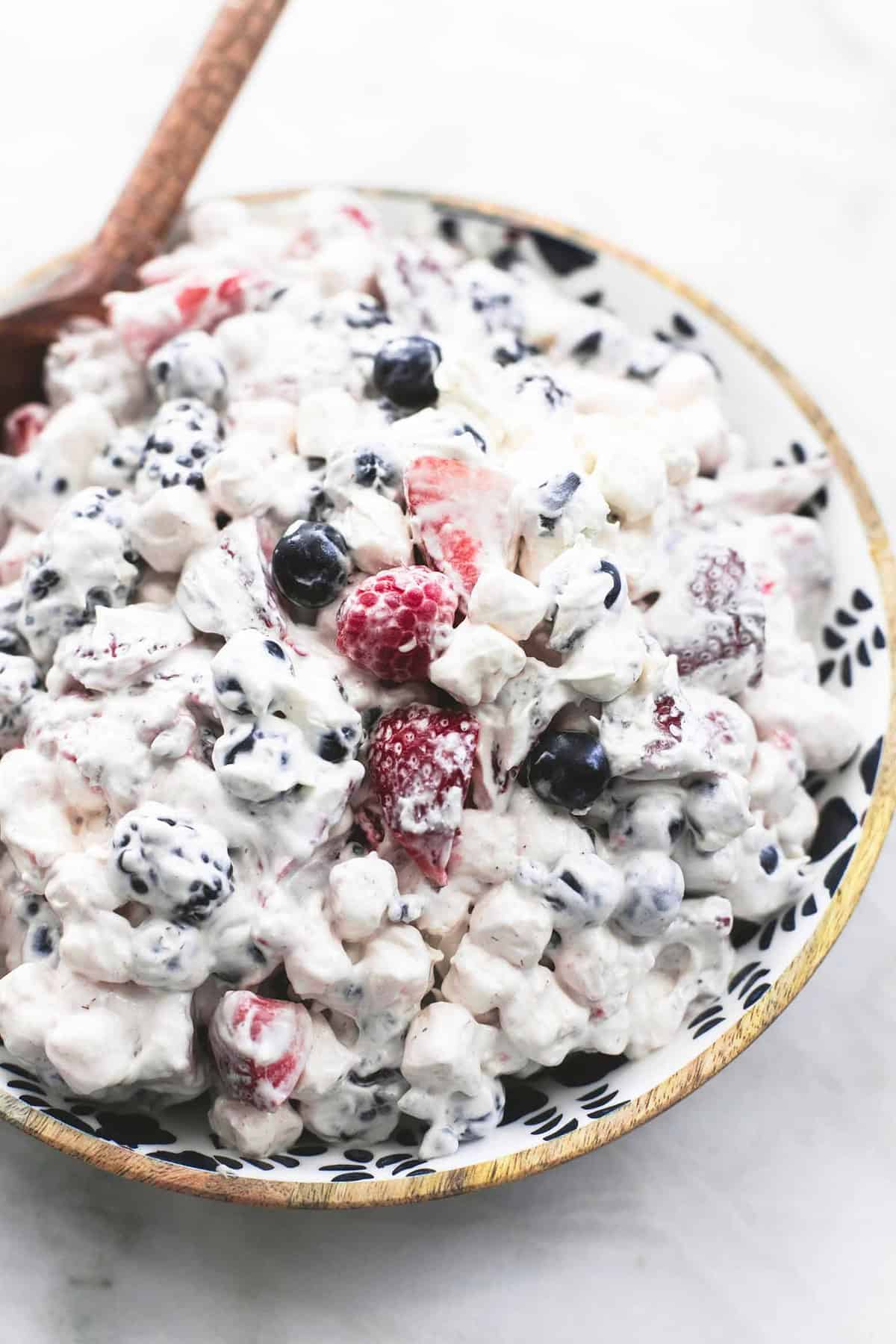 berry cheesecake salad with a wooden serving spoon in a bowl.