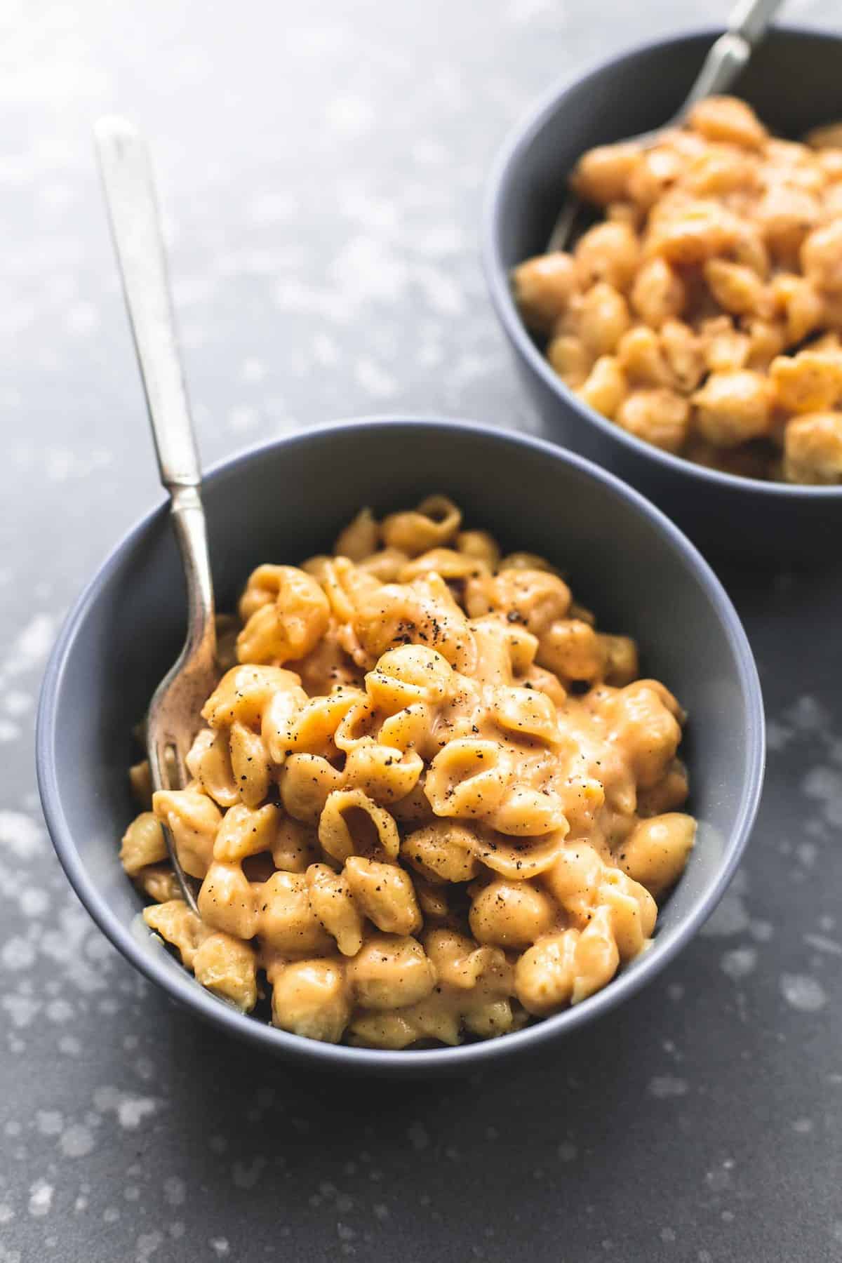 mac and cheese with a fork in a bowl with another bowl in the background.