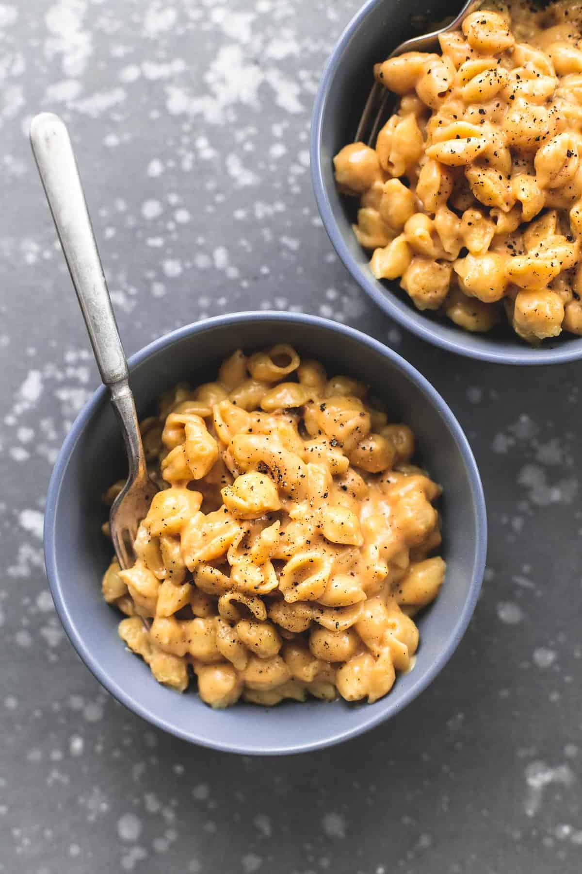 top view of creamy macaroni and cheese with a fork in a bowl with another bowl on the side.