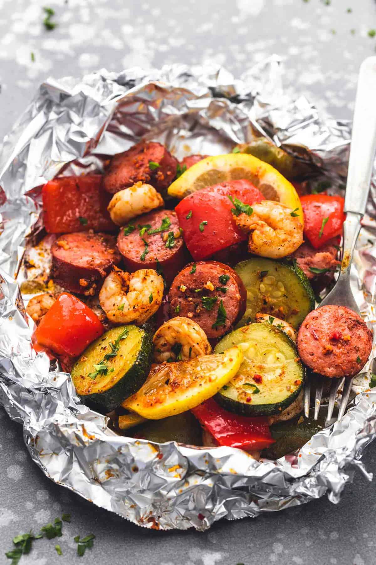 a shrimp sausage and veggie foil pack with a fork.