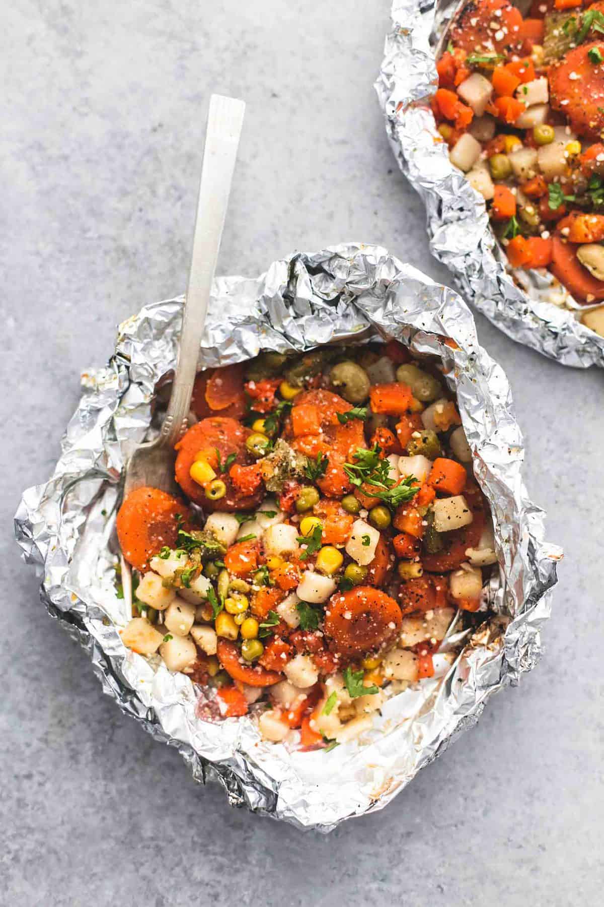 top view of a vegetable medley foil pack with a fork in it and another foil pack on the side.