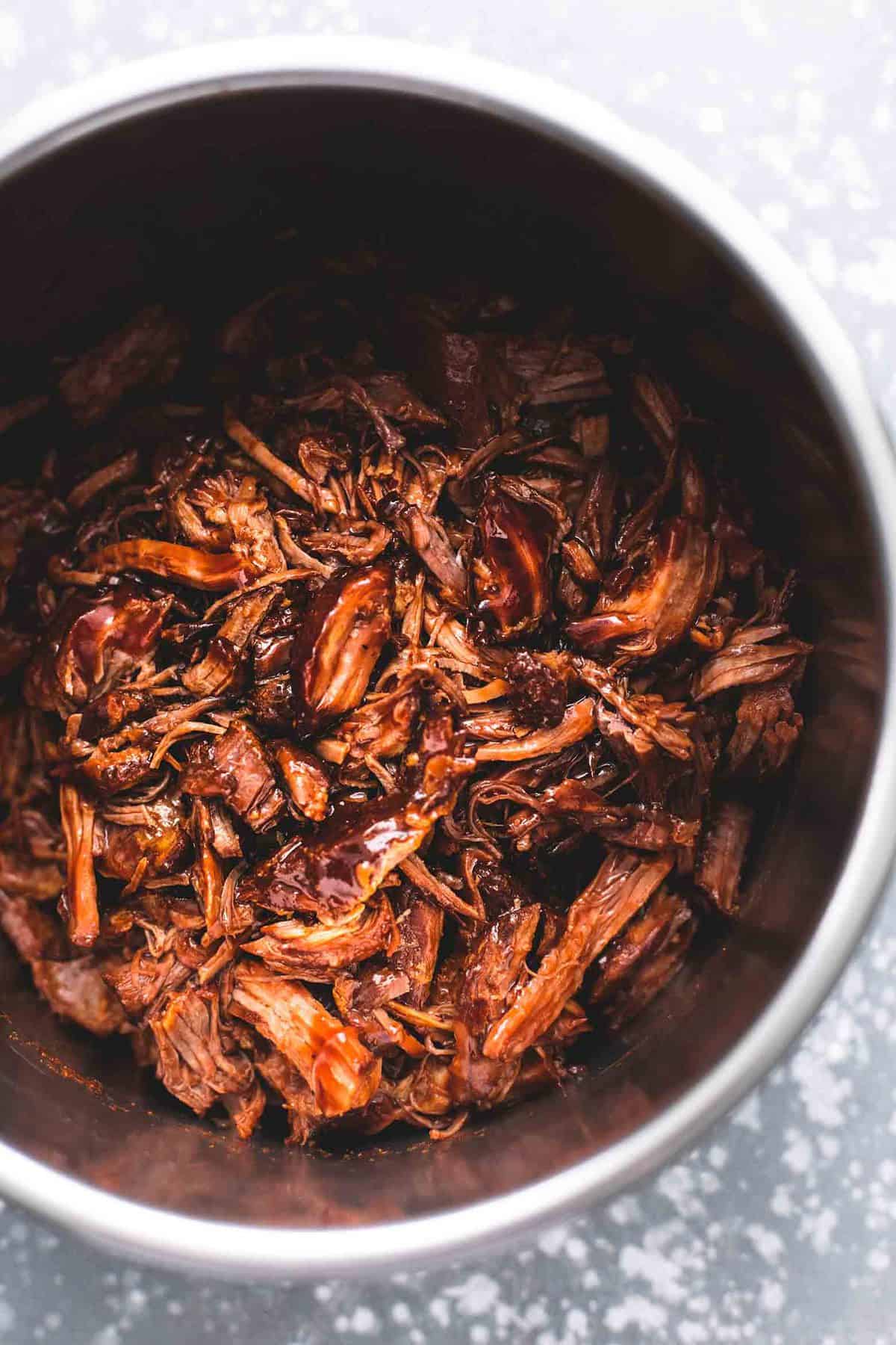 overhead view of shredded pork with brown sauce inside pressure cooker pot.