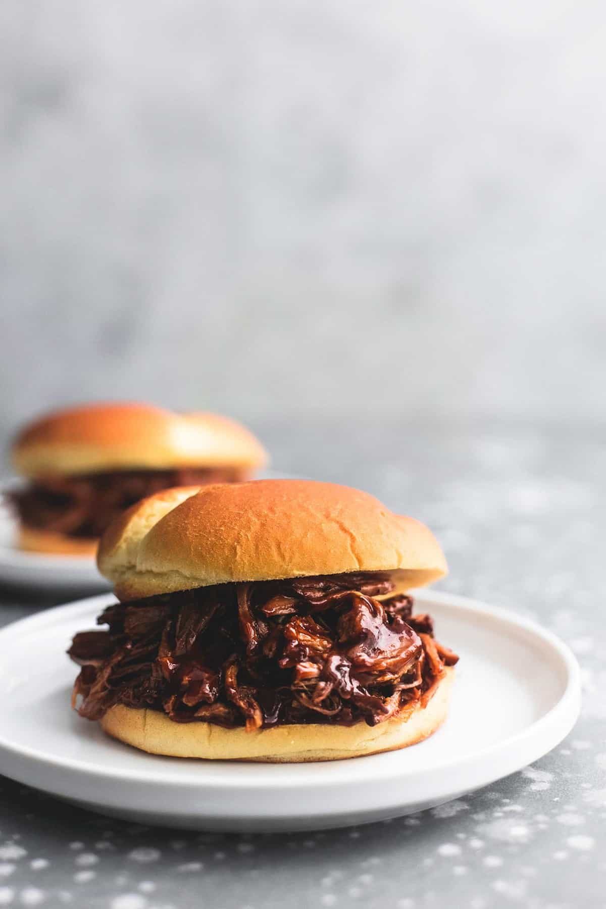 tabletop view of bbq pulled pork sandwich on a white plate.