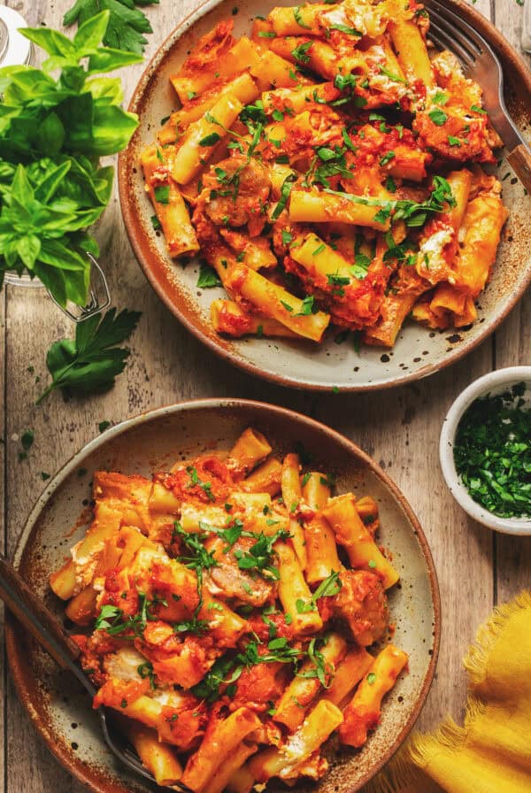 Overhead of two plates with baked ziti with sausage.