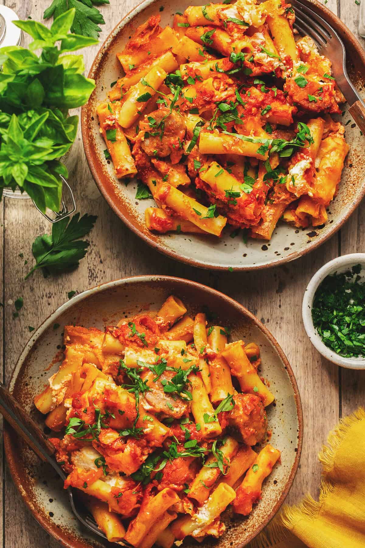Overhead of two plates with baked ziti with sausage.