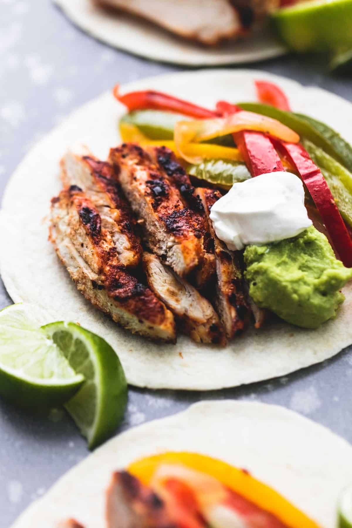 a chicken fajita with lime slices and more fajitas on the side.
