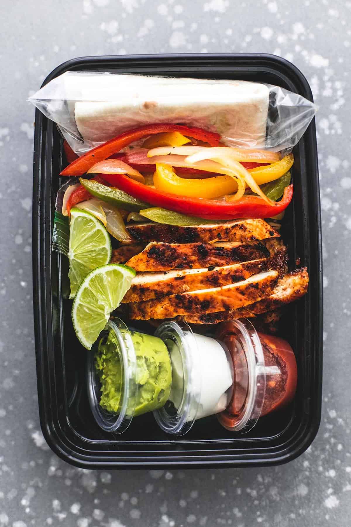 top view of meal prep chicken fajitas in a tupperware container.