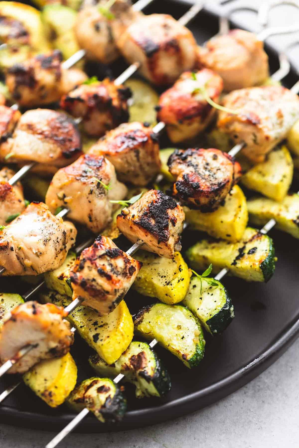 close up of herb chicken and veggie skewers on a plate.