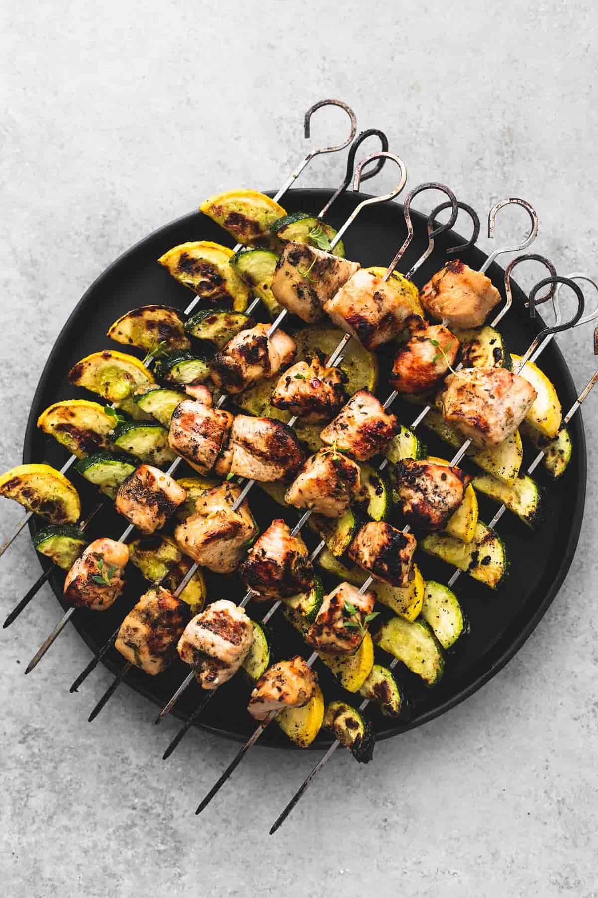 top view of herb chicken and veggie skewers on a plate.