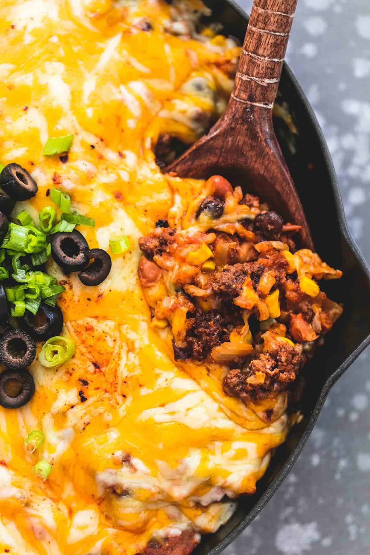 close up top view of Mexican beef and rice skillet with a wooden serving spoon in a skillet.