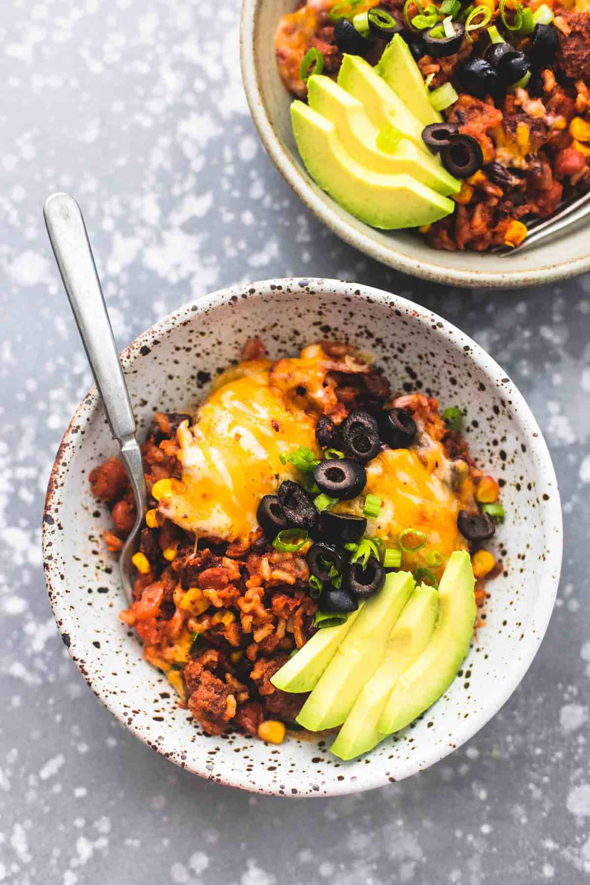 top view of Mexican beef and rice skillet and a fork in a bowl with more in another bowl on the side.