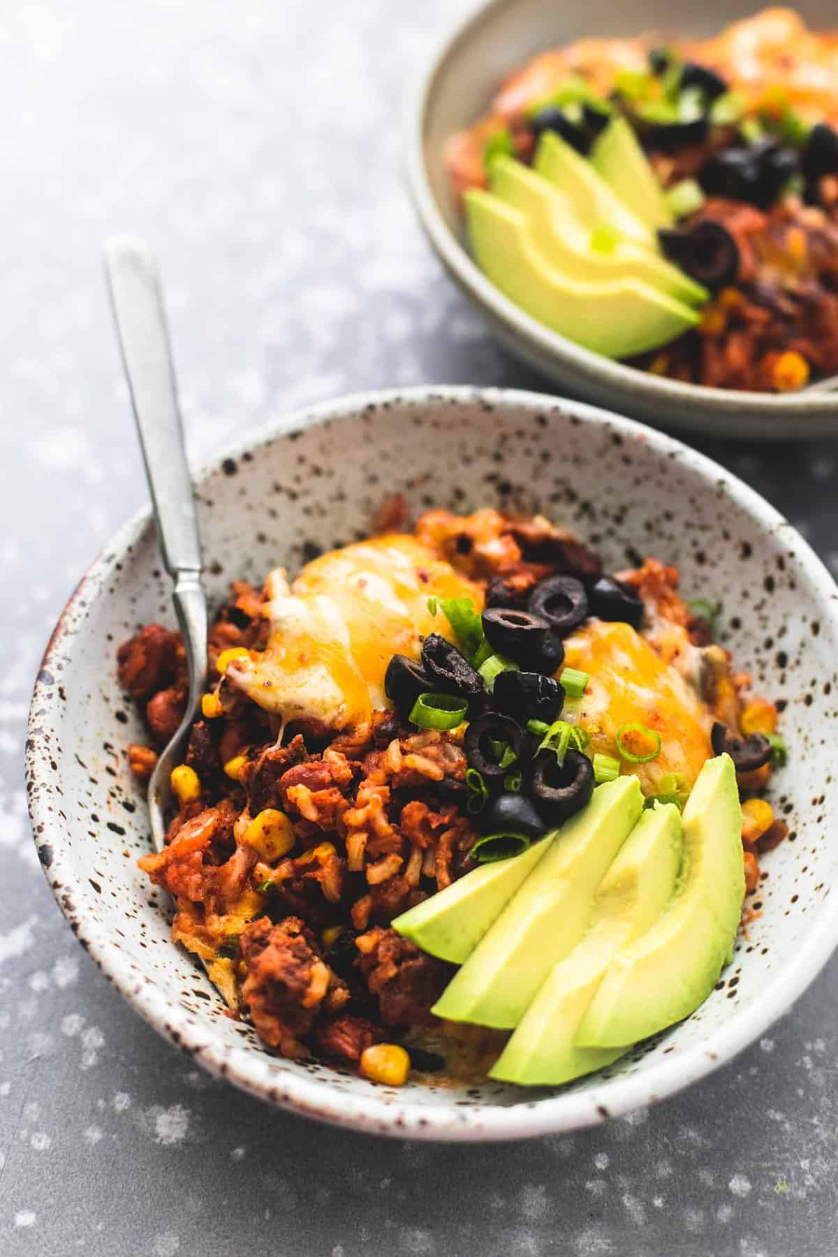 Mexican beef and rice skillet with a fork in a bowl with more in a other bowl in the background.