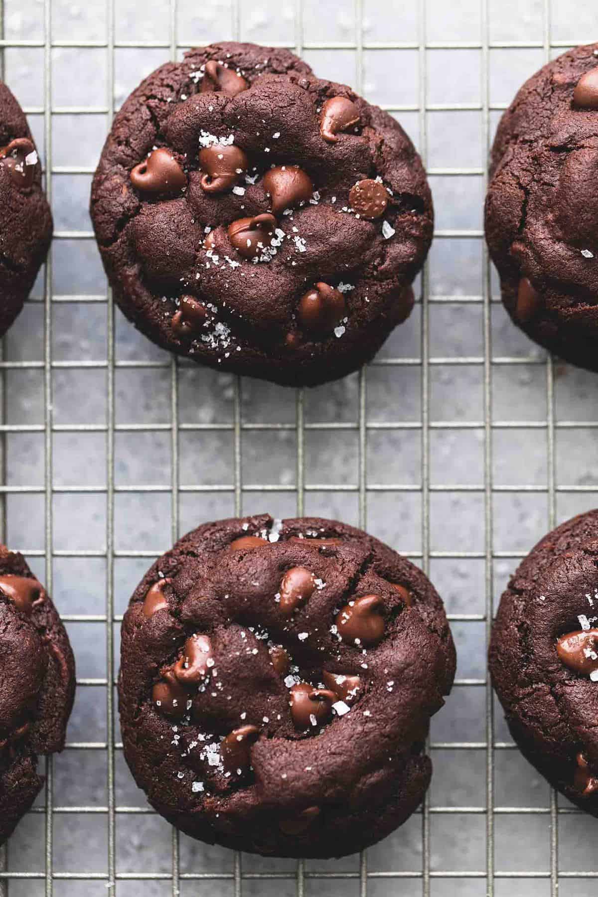 close up top view of salted caramel stuffed double chocolate cookies on a cooling rack.