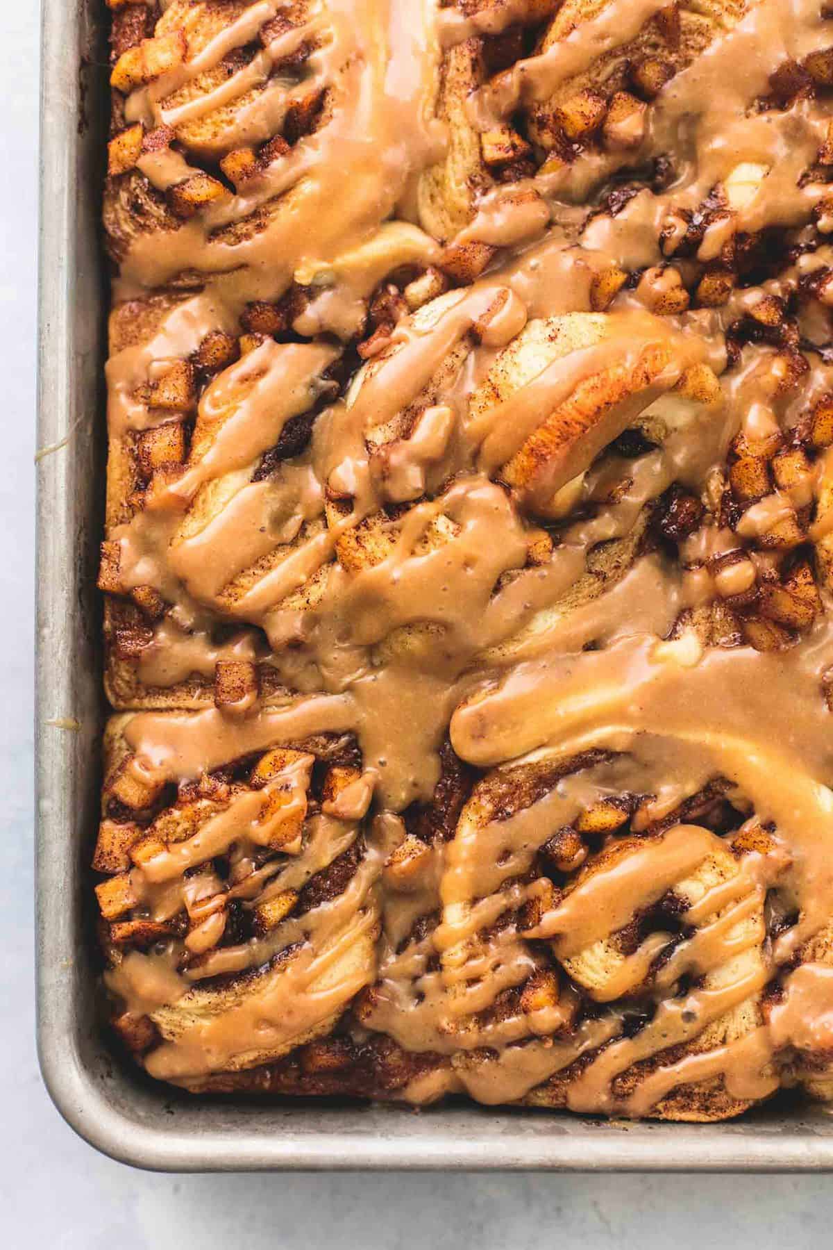 close up top view of apple pie cinnamon rolls on a baking sheet.