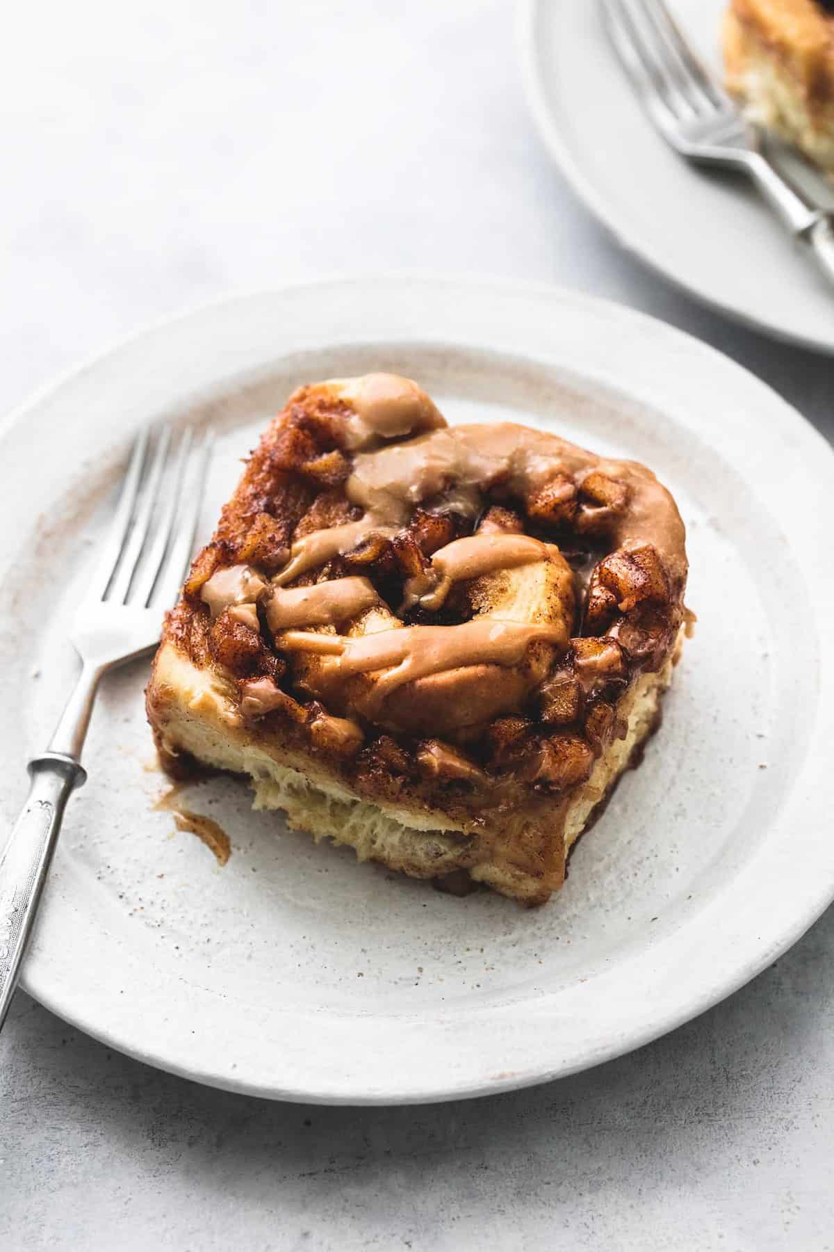 a apple pie cinnamon roll with a fork on a plate.