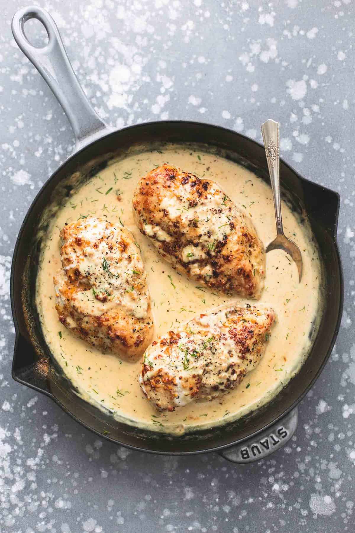 top view of lemon chicken in creamy dill sauce with a spoon in a skillet.