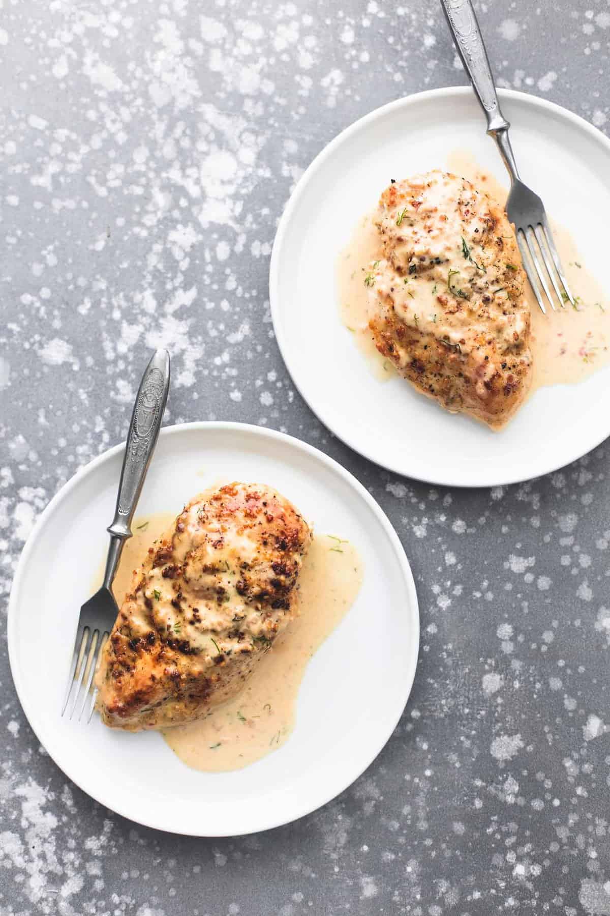 top view of pieces of lemon chicken in creamy dill sauce with forks on two plates.