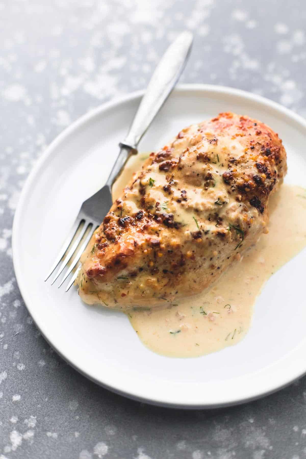 a piece of lemon chicken in creamy dill sauce with a fork on a plate.