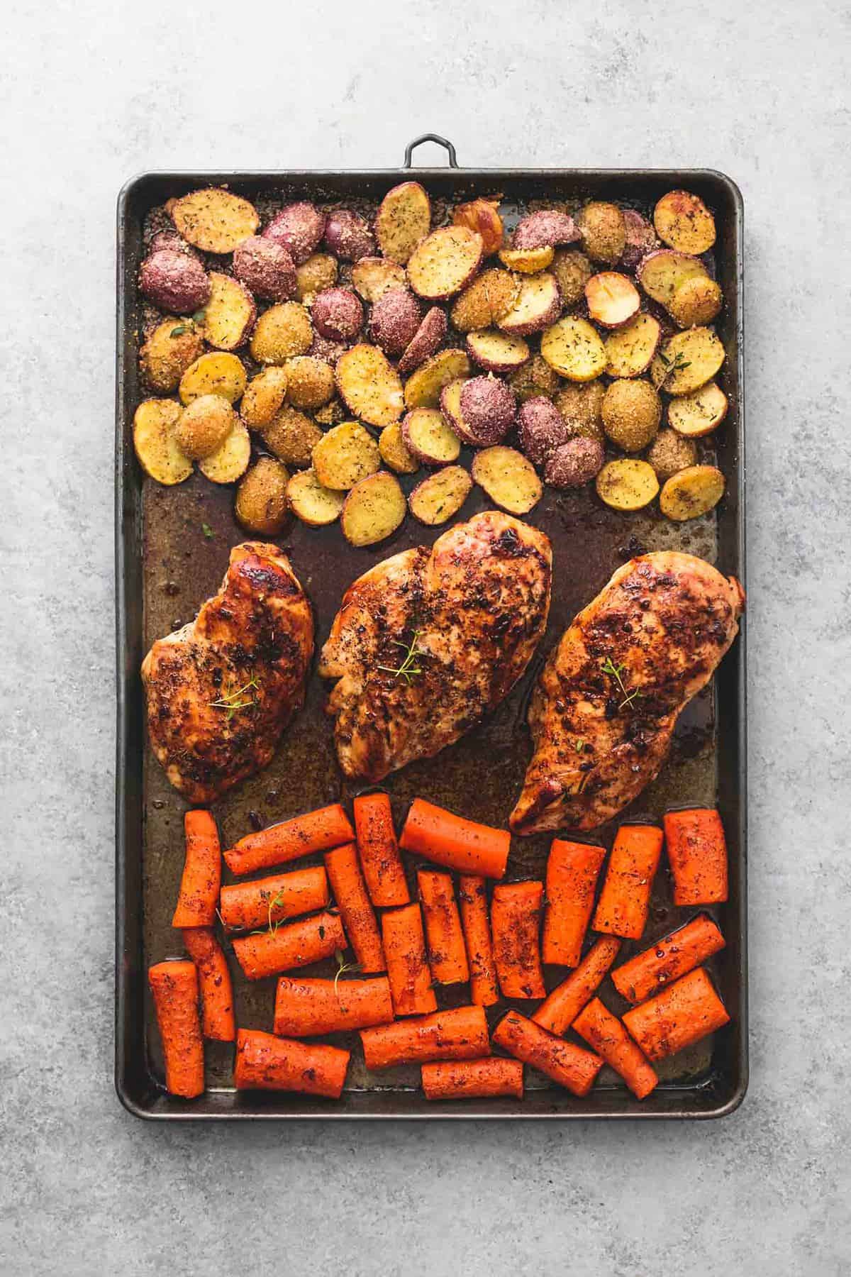 top view of sheet pan balsamic chicken with potatoes and carrots on a baking sheet.