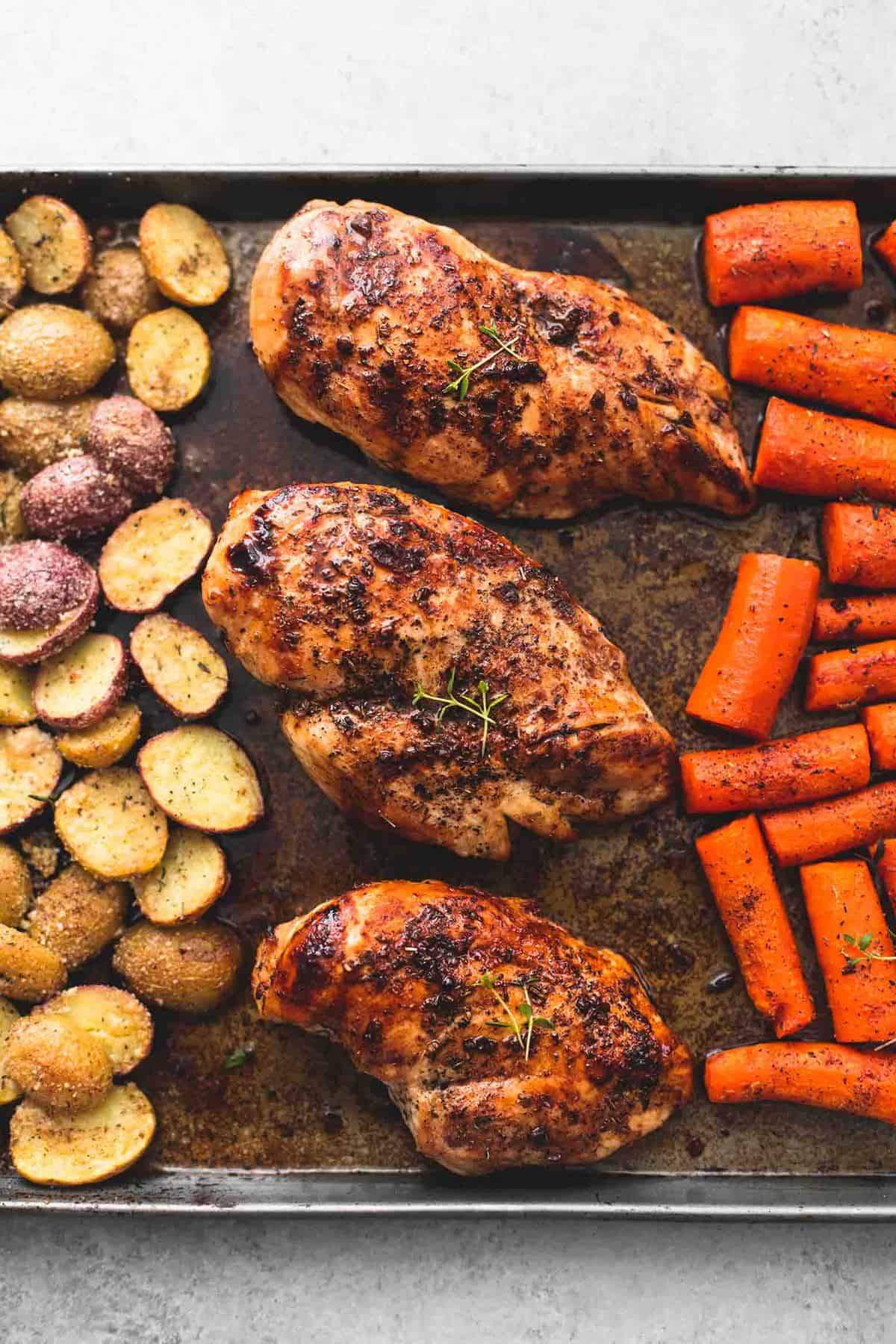 top view of sheet pan balsamic chicken with potatoes and carrots on a sheet pan.