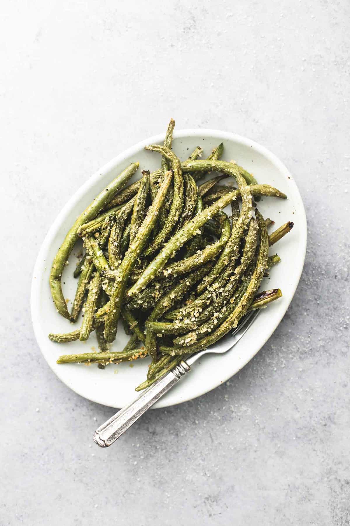 top view of crispy parmesan green beans with a fork on a plate.