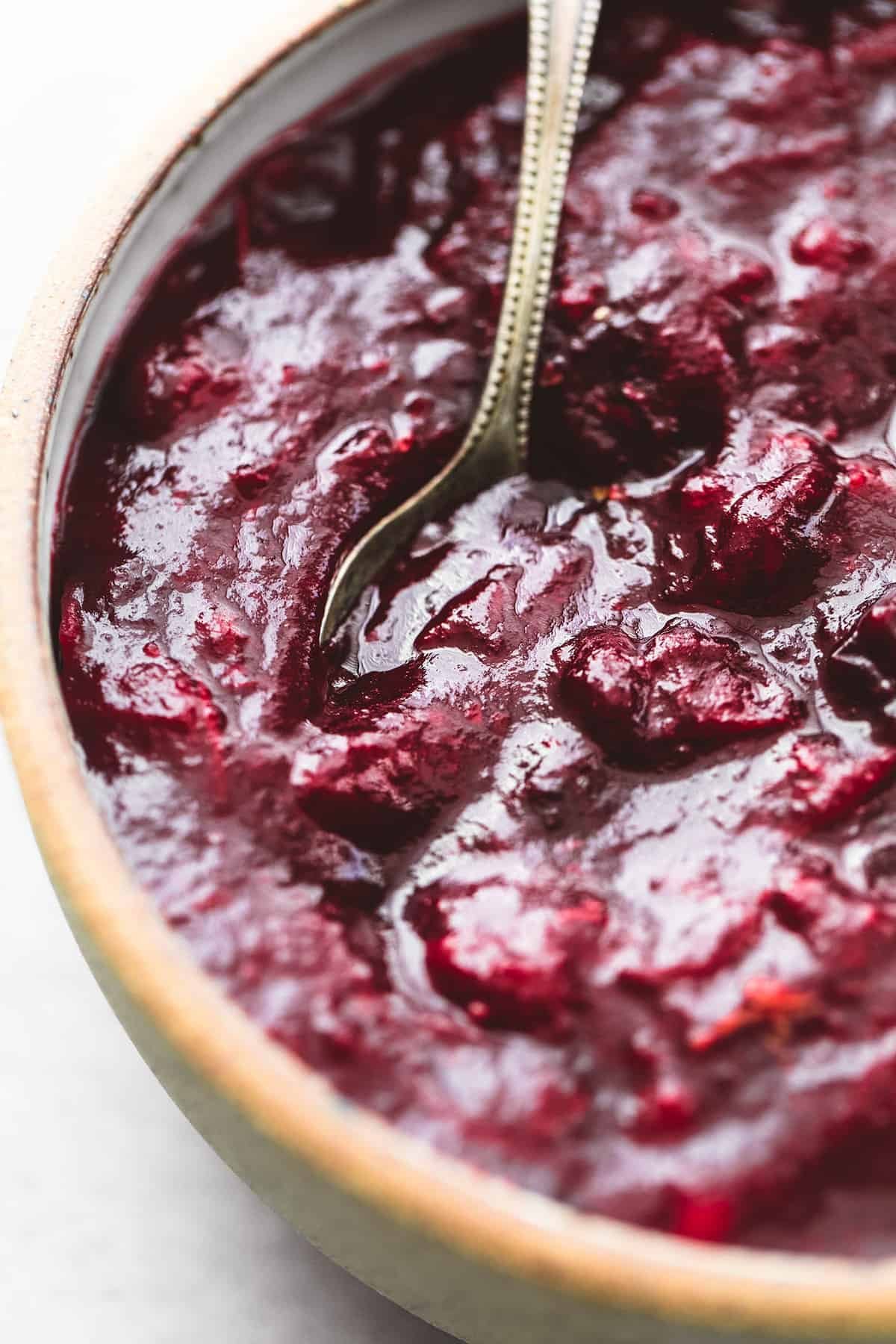 close up of cranberry sauce with a spoon in a bowl.