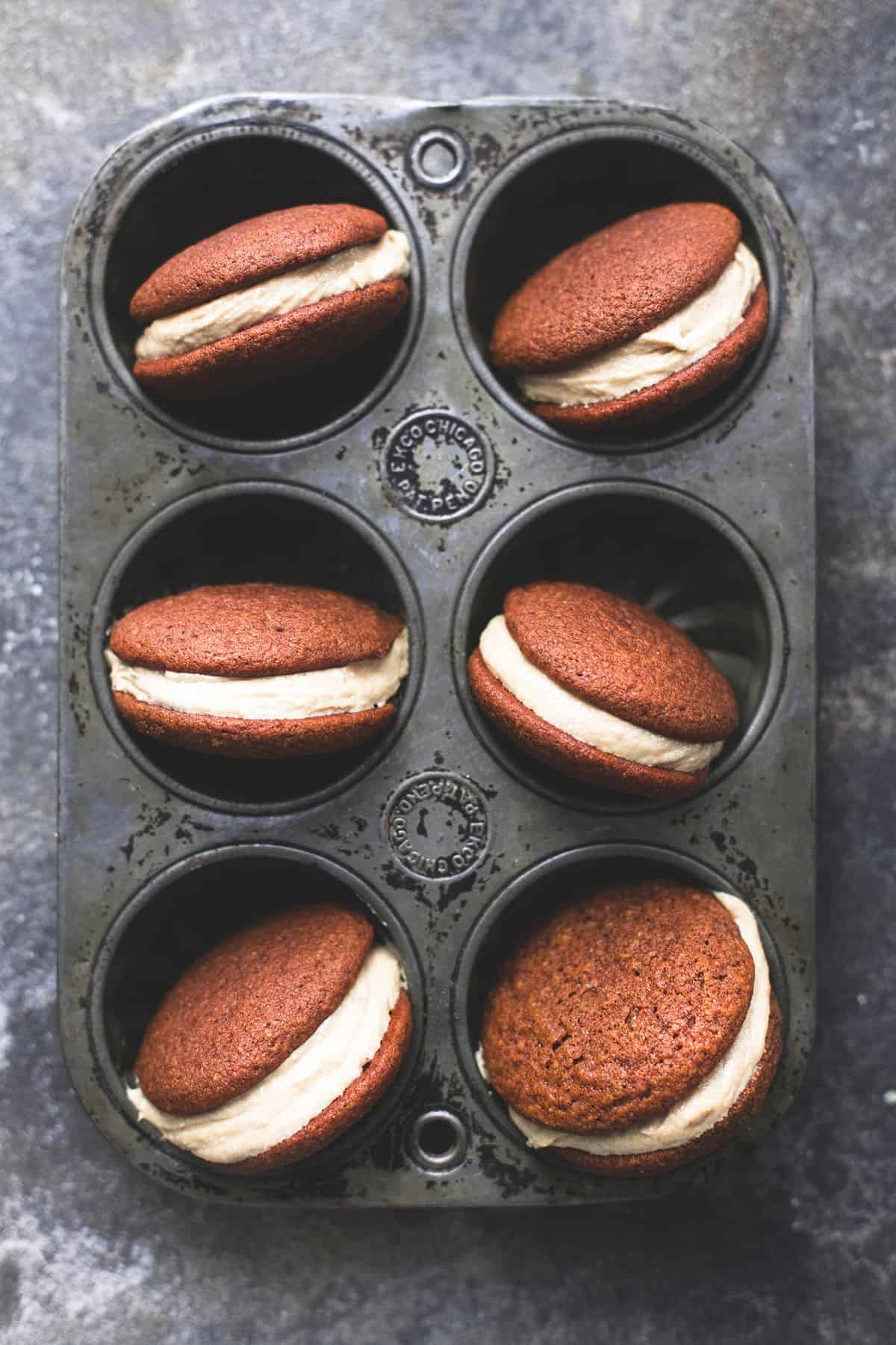 top view of gingerbread whoopie pies with caramel frosting in a muffin tin.