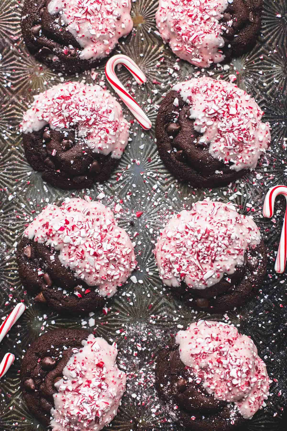 close up top view of double chocolate peppermint bark cookies and candy canes on a baking sheet.