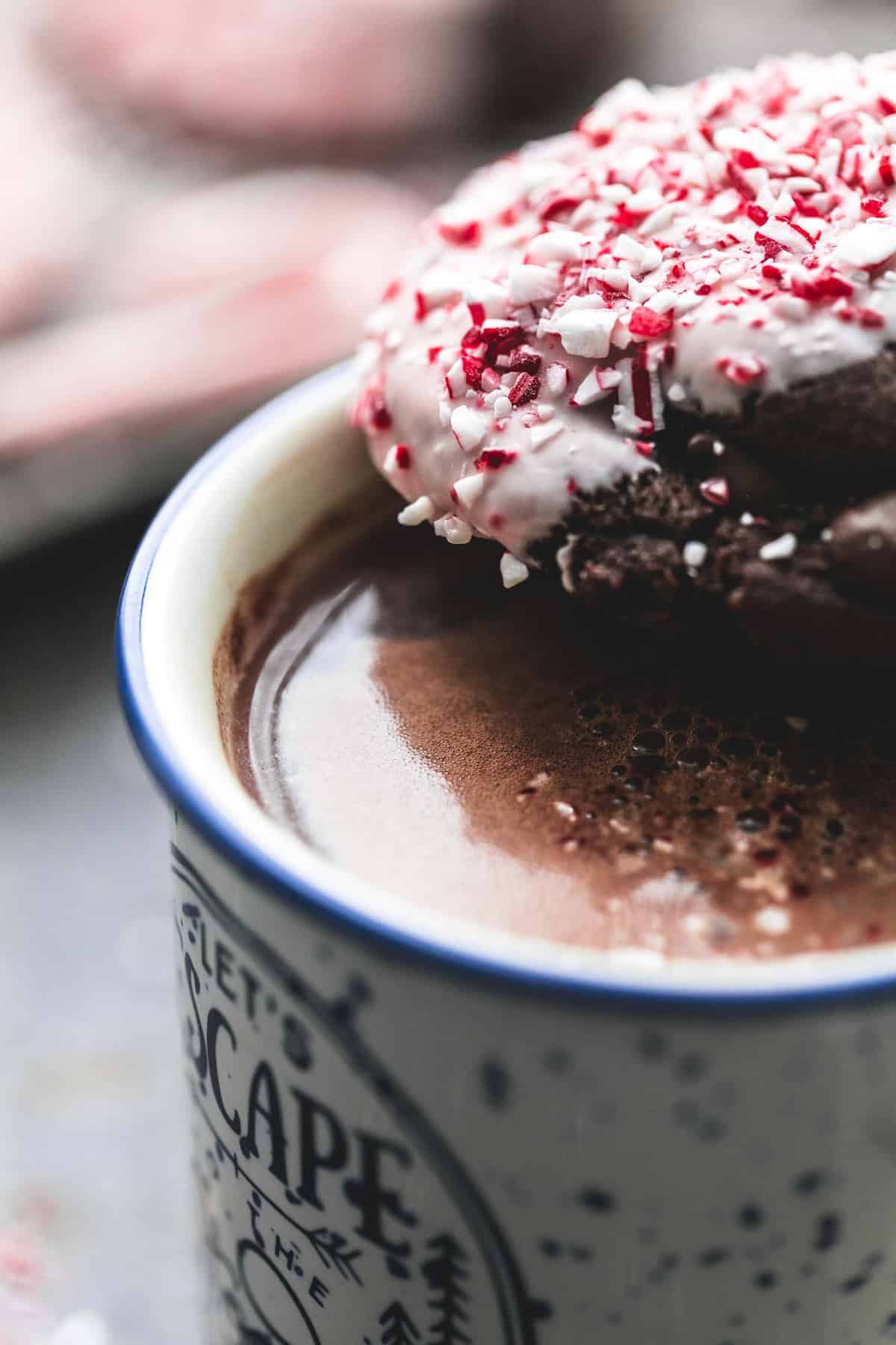 close up of a double chocolate peppermint bark cookie sitting on a mug of hot chocolate.