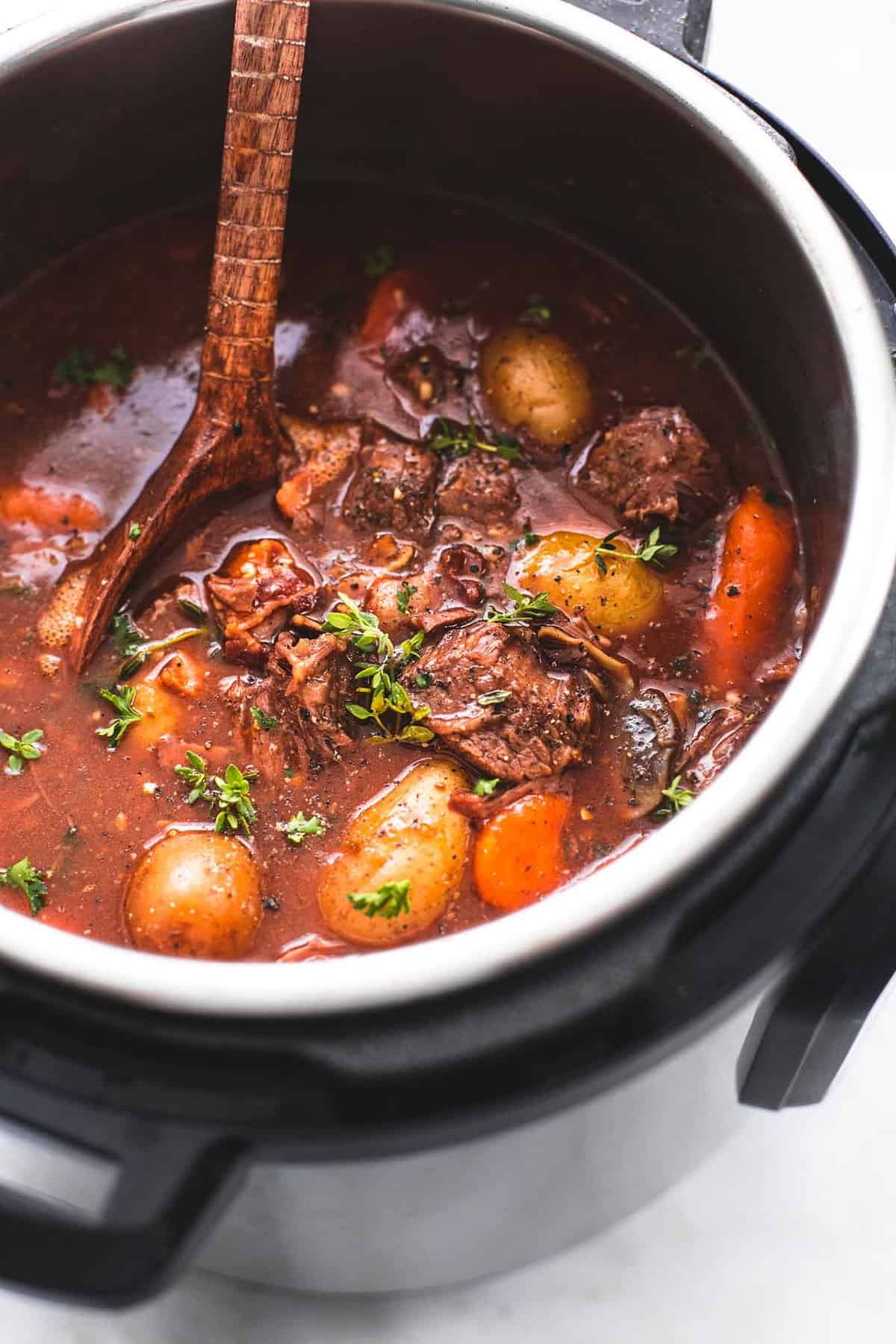rapid pot red meat bourguignon with a picket serving spoon in an rapid pot.
