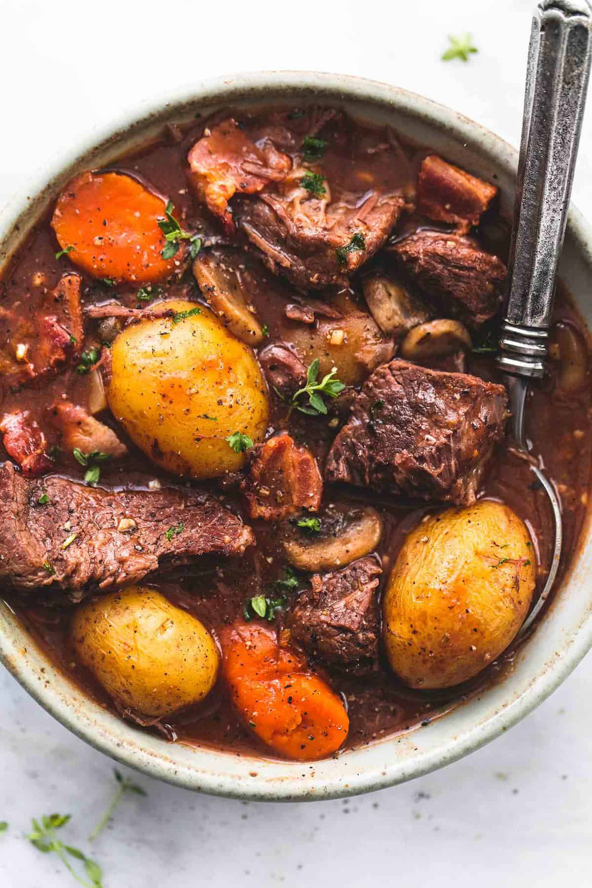 close up top view of instant pot beef bourguignon with a spoon in a bowl.