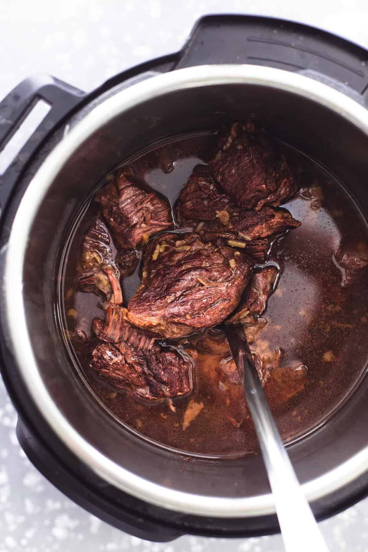 top view of pot roast and a serving spoon in an instant pot.