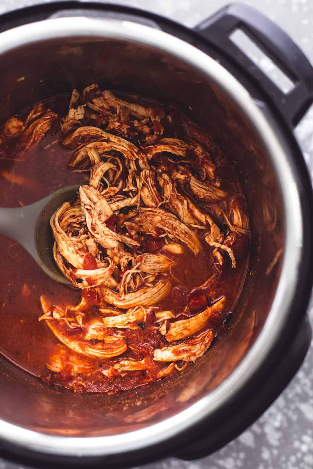 top view of shredded chicken and a serving spoon in an instant pot.