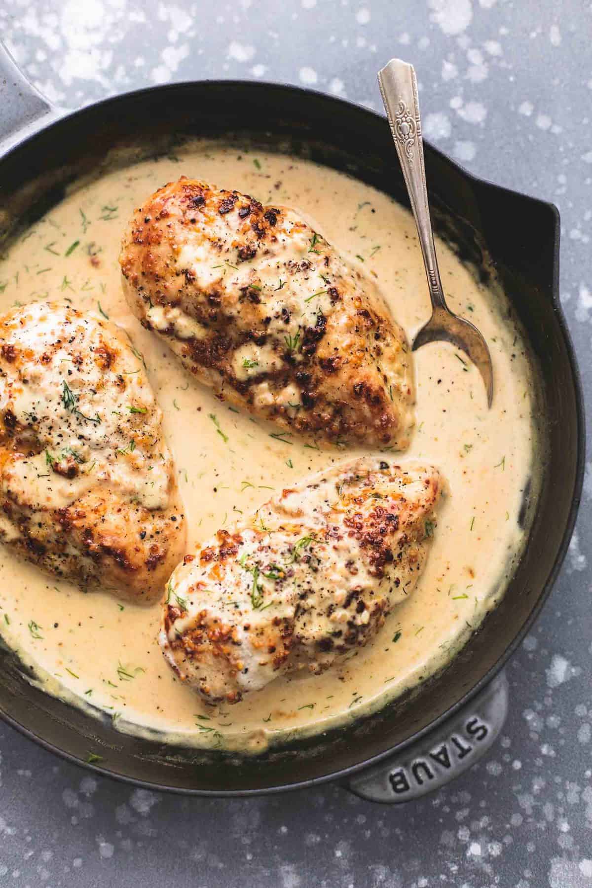 top view of lemon chicken in dill cream sauce and a spoon in a skillet.