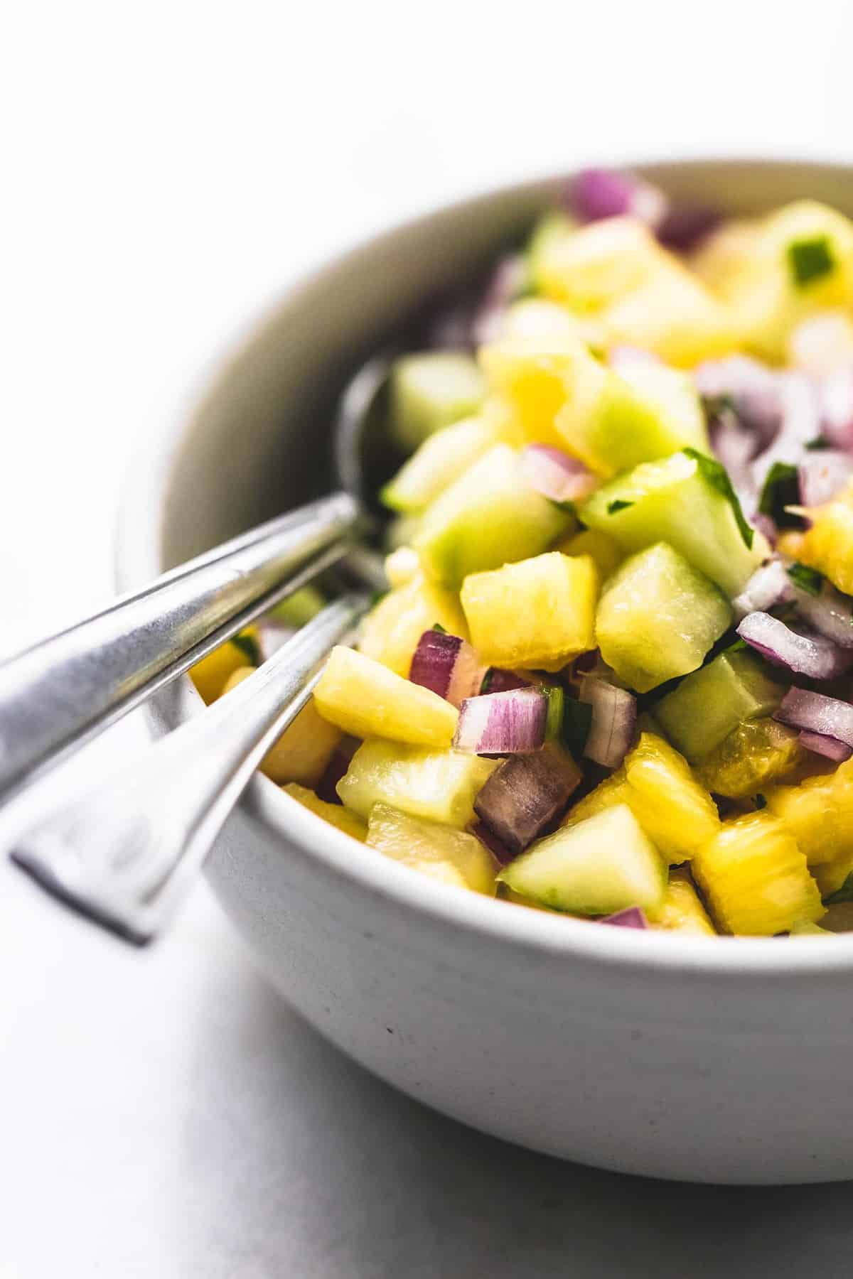 close up of pork tacos with pineapple salsa with spoons in a bowl.