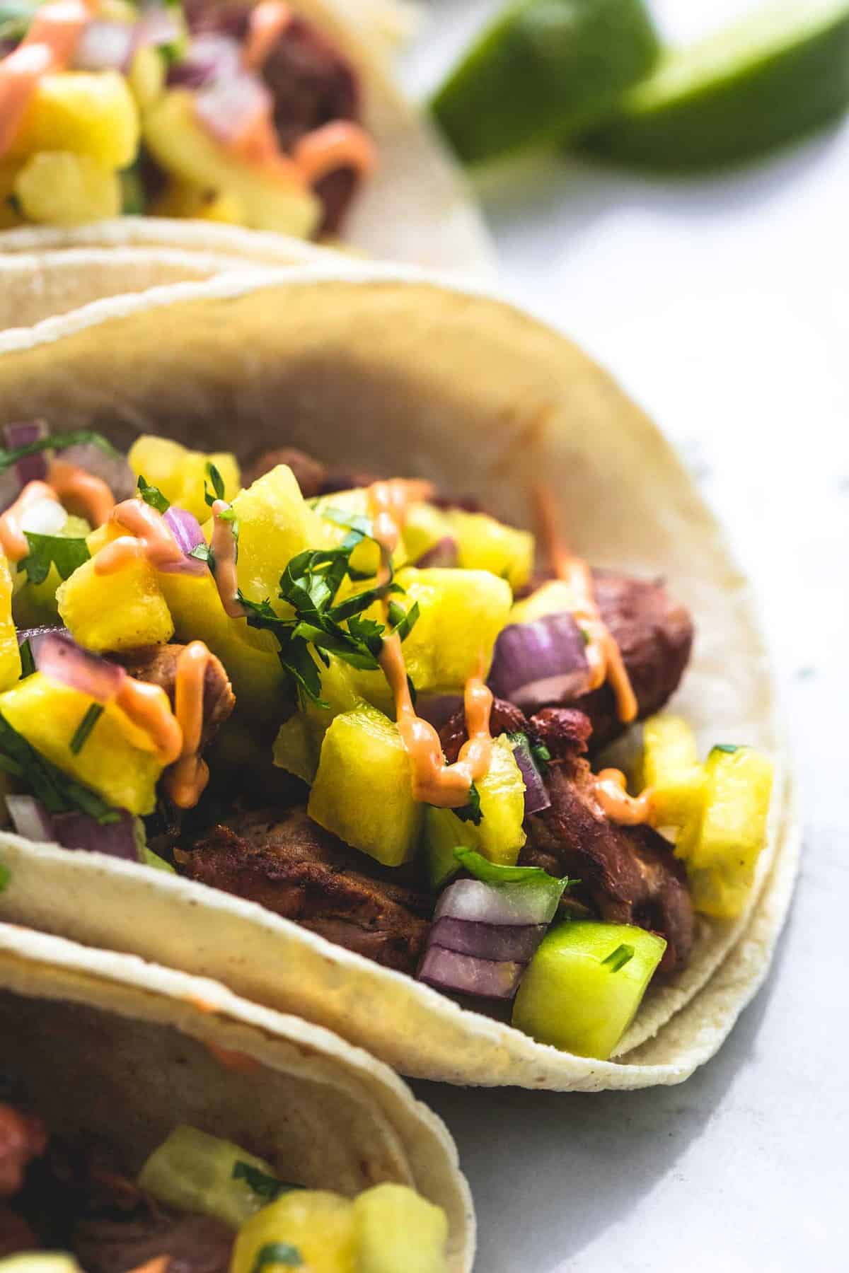 close up of a pork taco with pineapple salsa with more tacos on the side.