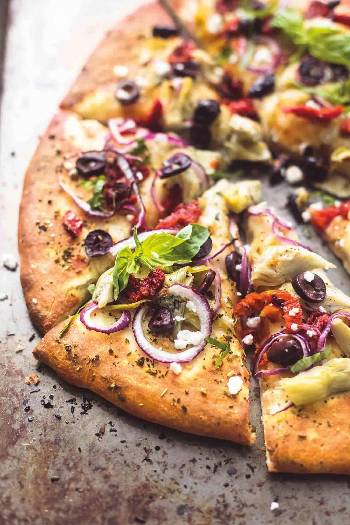 Mediterranean veggie pizza cut up in slices.